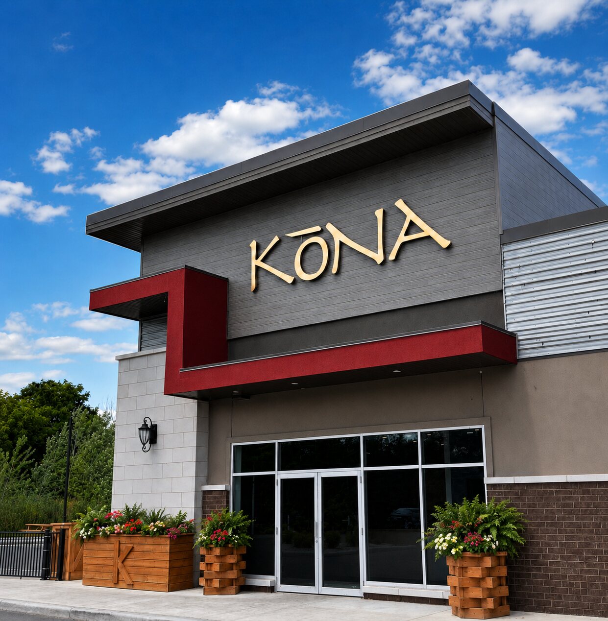 The Kōna Lakeshore front entrance — gold KŌNA lettering above glass doors flanked by planters.