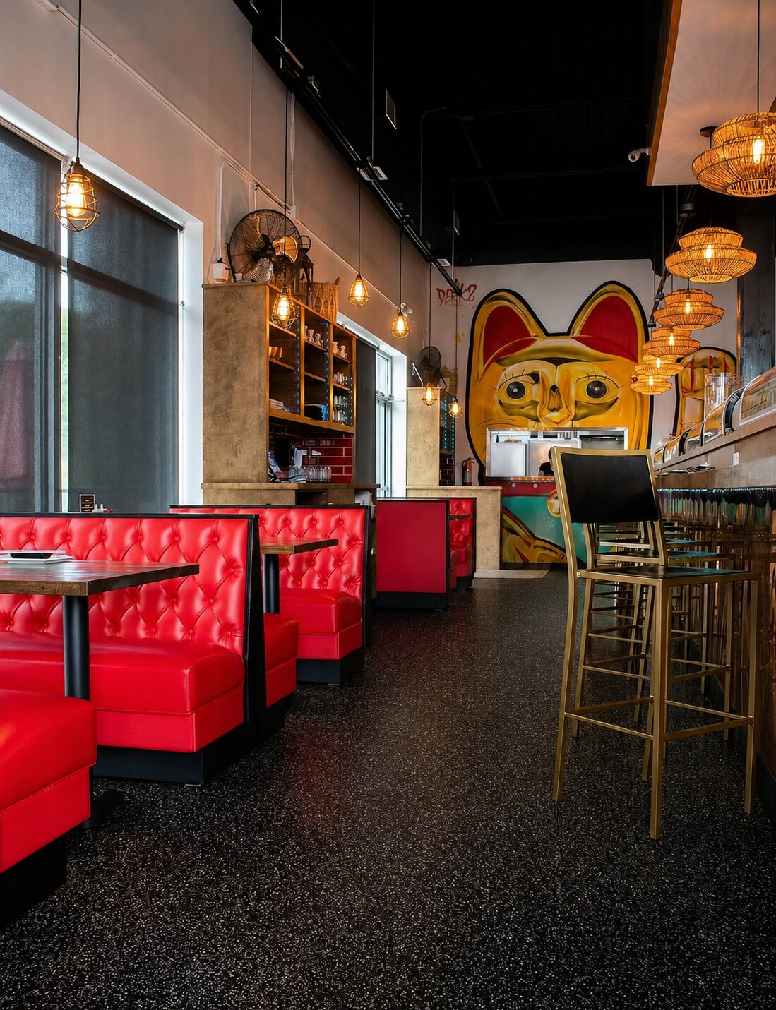 Red tufted booths and gold bar stools under moody lighting, with the golden lucky-cat mural as the backdrop.