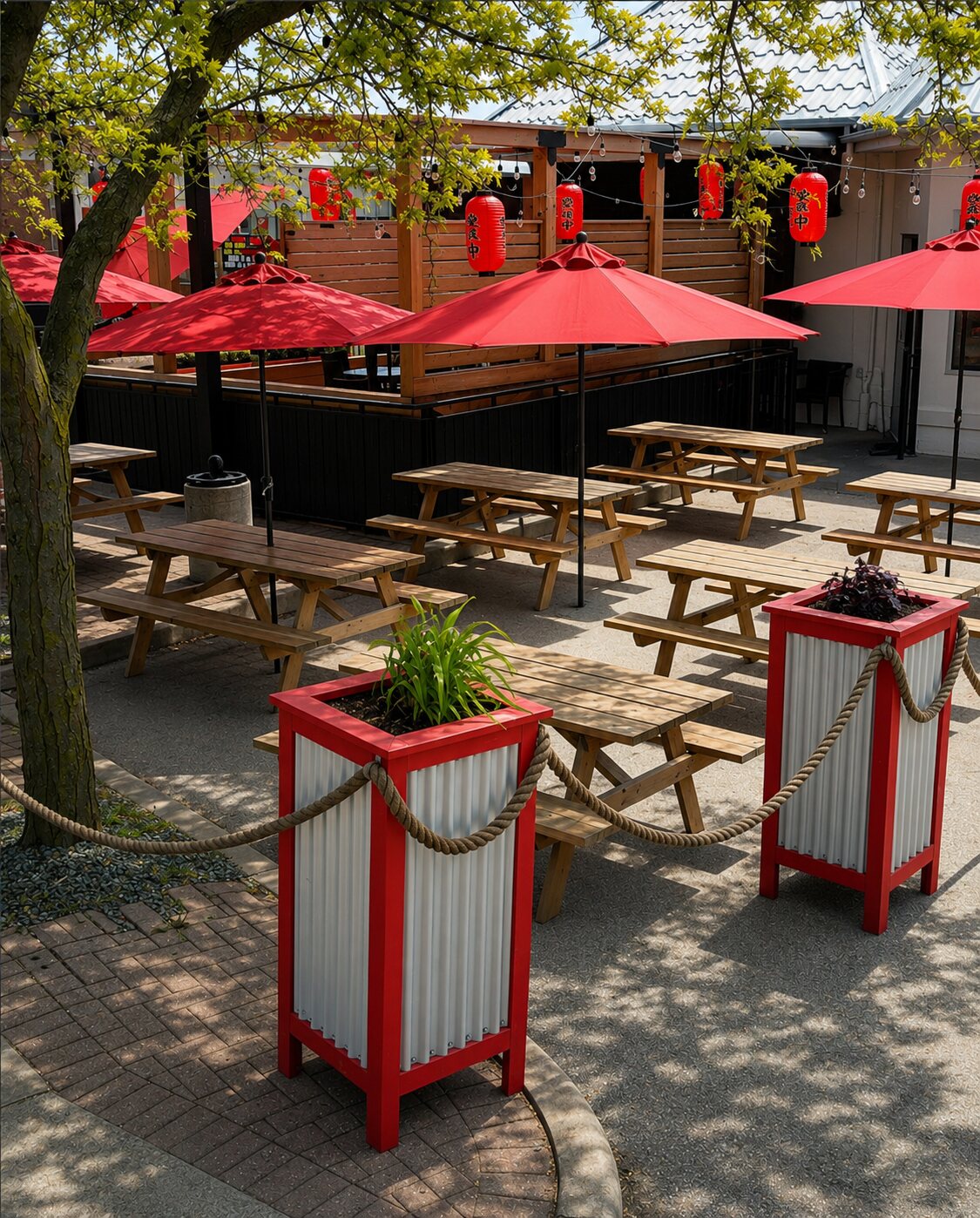 The outdoor patio strung with red Japanese lanterns and string lights over red umbrellas and picnic tables.