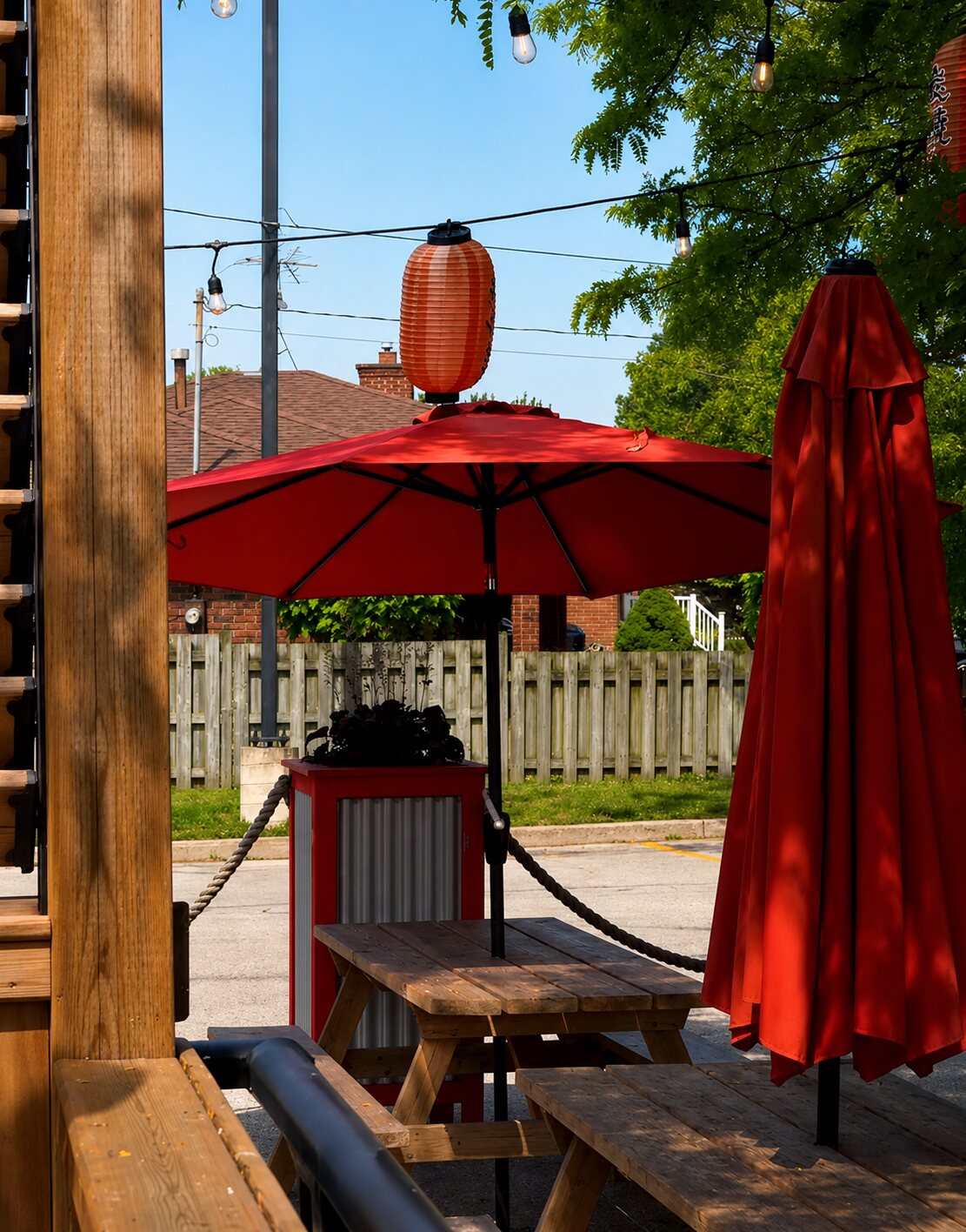 A sunny patio detail — a red umbrella and red lantern over a picnic table.