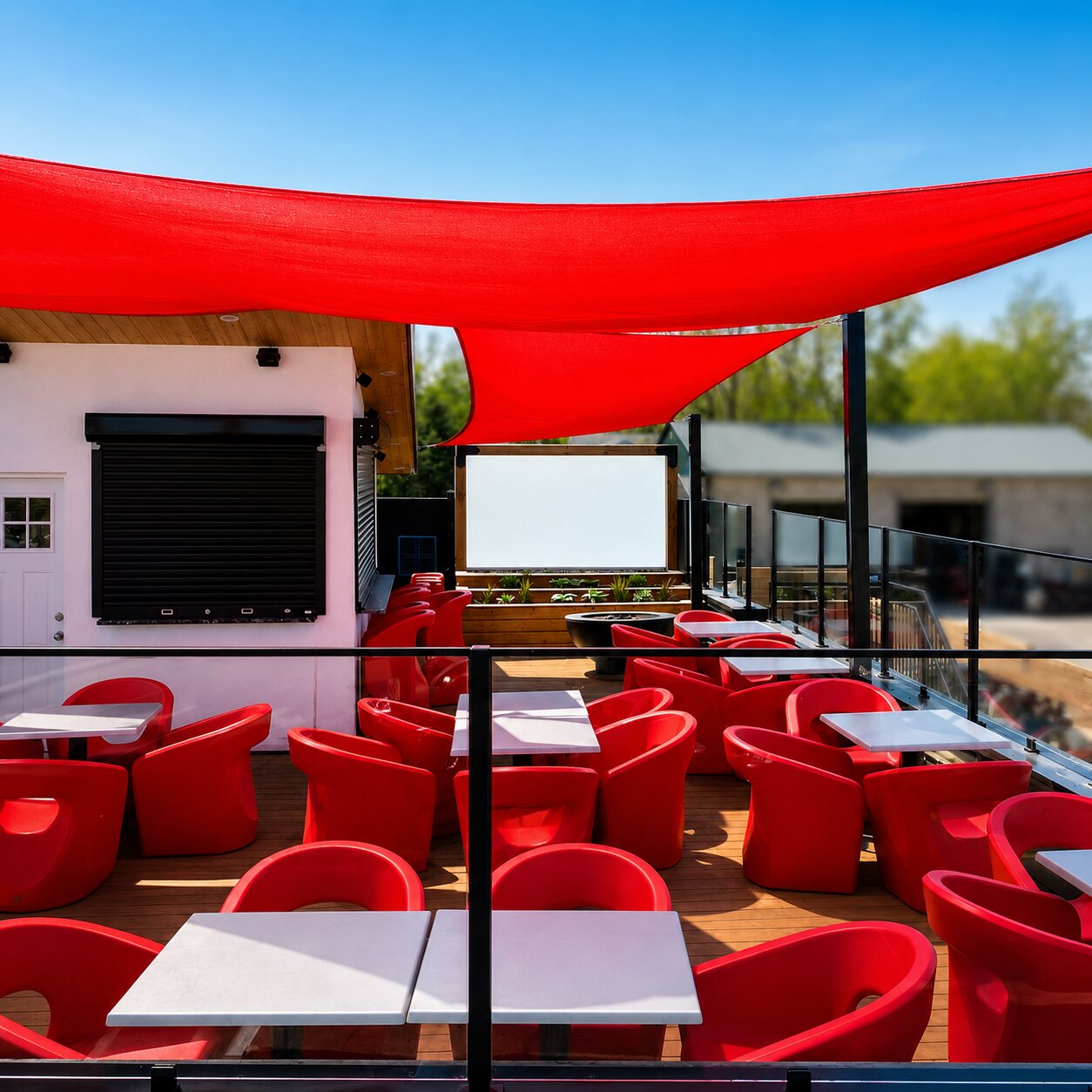 Red sail-cloth shades stretched over the rooftop patio against a bright blue sky, with the red lounge seating below.