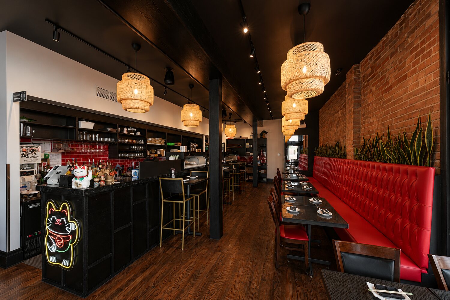 A red tufted banquette detail against exposed brick under warm rattan pendant light.